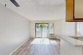 Located at 6150 El Cajon Blvd in San Diego, CA, this one-bedroom, one-bathroom unit offers a well-organized, efficiently laid-out living space across a single floor. The open-concept living, dining, and kitchen area is bathed in natural light, courtesy of a large sliding glass door that leads directly to a private balcony with outdoor views of surrounding greenery. Wood-look flooring runs throughout the living area, complemented by a textured ceiling and a ceiling fan. The kitchen is designed in a galley style with a wrap-around layout, featuring warm wood-toned cabinetry with white panel fronts, a white electric range, dishwasher, refrigerator, and a peninsula countertop that opens toward the living and dining space — ideal for casual dining or meal prep. The bedroom is a comfortable, carpeted retreat filled with natural light from a window fitted with vertical blinds. It includes a large sliding double-door closet, offering generous storage. Additional closet spaces are distributed throughout the unit, totaling four. The bathroom is clean and functional, featuring a wood-framed vanity with an integrated sink, a wall-mounted mirror, and a full shower-tub combination. Wood-look flooring carries into the bathroom, tying the space together with a cohesive aesthetic throughout.