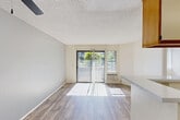 Located at 6150 El Cajon Blvd in San Diego, CA, this one-bedroom, one-bathroom unit offers a well-organized, efficiently laid-out living space across a single floor. The open-concept living, dining, and kitchen area is bathed in natural light, courtesy of a large sliding glass door that leads directly to a private balcony with outdoor views of surrounding greenery. Wood-look flooring runs throughout the living area, complemented by a textured ceiling and a ceiling fan. The kitchen is designed in a galley style with a wrap-around layout, featuring warm wood-toned cabinetry with white panel fronts, a white electric range, dishwasher, refrigerator, and a peninsula countertop that opens toward the living and dining space — ideal for casual dining or meal prep. The bedroom is a comfortable, carpeted retreat filled with natural light from a window fitted with vertical blinds. It includes a large sliding double-door closet, offering generous storage. Additional closet spaces are distributed throughout the unit, totaling four. The bathroom is clean and functional, featuring a wood-framed vanity with an integrated sink, a wall-mounted mirror, and a full shower-tub combination. Wood-look flooring carries into the bathroom, tying the space together with a cohesive aesthetic throughout.
