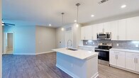 Located at 12400 Dutton Road in Midlothian, VA, this well-appointed 2-bedroom, 3-bathroom home offers a thoughtfully designed single-level layout with contemporary finishes throughout. The open-concept kitchen and living area serves as the heart of the home, showcasing white shaker cabinetry, a grey tile backsplash, stainless steel appliances, and a spacious center island with a quartz countertop and undermount sink, illuminated by elegant pendant lighting. Wood-look flooring flows through the main living areas, complementing the bright, neutral color palette. The living area features a door with sidelight window providing access to an outdoor balcony, allowing for natural light and outdoor views. The primary bedroom offers plush carpeting, a ceiling fan, and access to a walk-in closet with wire shelving, alongside a private en-suite bathroom featuring a large glass-enclosed shower with marble-style tile surround and brushed nickel fixtures. The second bedroom also features soft carpet and a ceiling fan. The bathrooms are finished with white vanities, quartz countertops, and wood-look flooring. Two closets provide generous storage throughout the home, rounding out a clean, modern living experience.