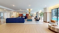 Located in the heart of Uptown Charlotte at 426 N Tryon St, this impressive single-floor amenity space spans nearly 6,000 square feet of thoughtfully designed communal areas. The welcoming lobby greets visitors with a distinctive reception desk adorned with textured gold paneling, bold botanical wallcovering, and elegant globe pendant lighting, setting a polished yet inviting tone throughout.

The expansive lounge area features rich hardwood flooring, a large navy sectional sofa centered around a statement fireplace, and floor-to-ceiling windows offering views of an outdoor terrace. Sheer drapery panels elegantly divide seating zones, while abundant natural light enhances the open, airy atmosphere.

A dedicated game room provides entertainment with a full-size billiards table, a built-in bar with counter seating, warm wood paneling, and vibrant decorative wallcovering. Adjacent to this, a café area showcases a fluted-wood counter, white marble surfaces, open gold shelving, and a cozy floral-wallpapered booth nook.

A bright creative studio offers communal high-top tables ideal for collaborative work or artistic pursuits, complemented by an easel and ample natural light. A private conference room stands out with an artistic mural-covered accent wall, a solid wood table, leather chairs, and a large display screen. Intimate nook seating areas with built-in marble-topped benches and soft blue walls provide quiet retreats throughout the space.