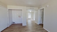 This single-floor residence offers a practical and efficient layout across three bedrooms and two bathrooms. The interior features a neutral color palette of soft whites and beige tones, creating a clean and cohesive aesthetic throughout. Hard surface wood-look flooring runs through the main living areas, entry, and kitchen, while plush carpet covers the bedrooms for added comfort.

The kitchen is functionally designed with white cabinetry providing ample storage, light countertops, a white electric range, built-in microwave, dishwasher, and a sink positioned beneath a window that allows natural light. The entry area includes a dedicated laundry hookup space and HVAC vents for central air distribution.

The generously sized primary bedroom features carpet flooring, a ceiling fan with light fixture, and a window fitted with blinds. The two additional bedrooms are carpeted and receive natural light through blinds-covered windows. Both bathrooms are finished with wood-look flooring; one includes a white vanity with mirror and lighting fixture, while the other features a full tub-shower combination with white tile surround. Two hallways connect the rooms, contributing to the home's organized flow.