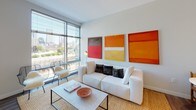 Located at 300 Harrison Avenue in Boston's vibrant South End neighborhood, this contemporary residence delivers a sleek, modern living experience across a single thoughtfully designed floor. The open-concept layout seamlessly connects the kitchen, dining, and living areas, creating a generous and cohesive space ideal for both everyday living and entertaining.

The kitchen is outfitted with high-gloss white cabinetry, stainless steel appliances, a dark tile backsplash, and a central island with pendant lighting — combining style and functionality in equal measure. Wide-plank hardwood flooring flows throughout the main living areas, adding warmth to the otherwise crisp, contemporary palette.

The living room is a standout, anchored by expansive floor-to-ceiling windows that frame sweeping views of the Boston skyline, flooding the space with natural light. The bedroom echoes this design with its own generous windows overlooking the city, offering an airy and restful retreat. The bathroom features large-format tile flooring, dark cabinetry with an integrated vanity, and a walk-in shower, providing a refined, spa-like atmosphere.

Clean lines, neutral tones, and an abundance of natural light define the overall ambiance of this well-appointed residence in one of Boston's most sought-after urban neighborhoods.