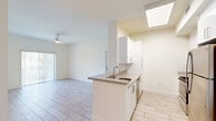 Located at 26710 SW 140th Ave in Homestead, FL, this 3-bedroom, 2-bathroom residence offers a bright, well-organized single-floor layout designed for comfortable living. Light-toned wood-look tile flooring runs throughout the home, creating a clean and cohesive aesthetic. The open-concept kitchen features white cabinetry, a peninsula with a built-in sink and countertop seating, stainless steel appliances including a refrigerator and range, and a skylight overhead that bathes the space in natural light. The kitchen flows seamlessly into the living area, which is equipped with a ceiling fan and sliding glass doors leading to a private balcony. In-unit laundry with a full-size washer and dryer is conveniently located just off the main living space. The three bedrooms are well-proportioned, each featuring ceiling fans, natural light from windows with vertical blinds, and generous closet space — five closets total are distributed throughout the unit. The primary bedroom includes a mirrored closet and direct outdoor views. Both bathrooms are finished with white vanities, matching tile flooring, and tub-shower combinations. The overall ambiance is light, airy, and move-in ready, reflecting a modern and functional design sensibility.