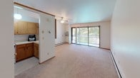 Located at 4057 S 35th St in Greenfield, Wisconsin, this single-floor unit offers a practical and comfortable layout designed for easy everyday living. The open living and dining area is generously sized, featuring neutral carpet flooring, a ceiling fan, and a large sliding glass door that floods the space with natural light and provides views of the surrounding greenery. Baseboard heating runs throughout the unit, ensuring warmth during Wisconsin winters, while a wall-mounted air conditioning unit keeps the living area comfortable in warmer months. A staircase with a wood railing is visible within the space, along with a louvered closet that adds convenient storage.

The kitchen is thoughtfully laid out with oak cabinetry spanning both upper and lower sections, light countertops, and white appliances including a gas range and refrigerator. A double sink and tile-style flooring complete the functional cooking space.

The bedrooms are carpeted and well-proportioned, each featuring closets for ample storage. One bedroom includes a large window with vertical blinds, offering natural light and outdoor views.

The bathroom is accessed via a hallway and features a wide oak vanity with generous counter space, a large mirror, and carpeted flooring, maintaining the warm, wood-toned aesthetic found throughout the unit.