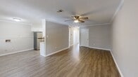This well-appointed 2-bedroom, 1-bathroom single-story home in Little Rock, Arkansas offers a comfortable and functional layout. Throughout the space, warm wood-look flooring creates a cohesive and inviting atmosphere, complemented by neutral gray walls and crisp white trim and crown molding in the main living areas.

The open living room is spacious and airy, featuring a ceiling fan with light fixture, textured ceilings, and seamless flow into the kitchen area. The kitchen is efficiently designed with white cabinetry, light quartz-style countertops, a mosaic tile backsplash, a black electric range, and a stainless steel refrigerator — offering ample storage and prep space.

Both bedrooms are generously sized, each featuring ceiling fans, natural light from windows with blinds, and neutral tones that provide a calm and restful environment. The primary bedroom includes closet access and crown molding details. The full bathroom is neatly finished with a tiled tub/shower surround in warm earthy tones, a single-sink vanity with white cabinetry, and wood-look flooring. The overall design is clean, practical, and move-in ready.