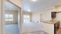 Located at 2500 S Public Rd in Lafayette, Colorado, this three-bedroom, one-bathroom residence offers a practical and well-organized single-floor layout. The open living area is bright and welcoming, featuring soft carpeting underfoot and a sliding glass door that leads to a private balcony, filling the space with natural light. Adjacent to the living room, the kitchen is appointed with a peninsula island featuring an integrated sink and a tan countertop, dark cabinetry, and black appliances including a range, microwave, and refrigerator. Wood-look vinyl flooring anchors the kitchen area, creating a clean transition from the carpeted living space. The three bedrooms are comfortably sized, each featuring plush carpet, closets with built-in shelving and rods, and ceiling fans for added comfort. The primary bedroom includes a sliding closet and direct access to additional rooms. The bathroom is finished with wood-look vinyl flooring, dark vanity cabinetry with a countertop sink, a large mirror, and a separate toilet area. The overall palette of warm beige tones and neutral finishes throughout creates a cohesive, move-in-ready atmosphere suited for comfortable everyday living.