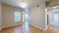 This thoughtfully designed 1-bedroom, 1-bathroom unit offers a comfortable and functional single-floor layout. The living room features warm wood-look luxury vinyl flooring, a ceiling fan with light fixture, and multiple windows fitted with blinds that invite ample natural light. A glass door leads directly to a private balcony, extending the living space outdoors. The galley-style kitchen is well-equipped with stainless steel appliances — including a range, microwave, refrigerator, and dishwasher — paired with crisp white shaker cabinetry, white subway tile backsplash, and light quartz countertops. The bedroom is generously sized, finished with plush carpeting, a ceiling fan, and a large window offering natural light. It connects to a spacious walk-in closet outfitted with wire shelving along three walls, providing excellent storage capacity. The bathroom features a full tub-shower combination with white tile surround, wood-look flooring, white cabinetry, and a quartz vanity countertop. Neutral tones and clean finishes throughout lend the space a bright, move-in-ready appeal.