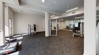 Located at 417 Centinela Ave in Inglewood, California, this fitness center offers a well-equipped, single-floor workout facility designed with both functionality and comfort in mind. The space features a clean, modern aesthetic with crisp white walls, structural columns, and durable dark rubber flooring suited for high-impact exercise.

Natural light fills the cardio area through large windows that frame views of the surrounding neighborhood, creating an open and energizing atmosphere. Two treadmills are positioned near the windows to take advantage of the natural light and outdoor views, making cardio sessions more engaging.

The strength training area is generously sized, providing ample room to move freely between a variety of cable and resistance machines. A full rack of dumbbells is neatly organized along a mirrored wall, which spans a significant portion of the gym and enhances the sense of space while allowing users to monitor their form during workouts.

Overhead, recessed and linear LED lighting ensures consistent illumination throughout the entire facility. The open floor plan allows for flexible use of the space, accommodating both machine-based and free-weight training with ease. The overall ambiance is bright, clean, and professional, offering an inviting environment for a comprehensive fitness routine.