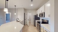This single-floor residence at 551-103 Snowmass Loop in Garner, NC offers a thoughtfully designed layout with modern finishes throughout. The open-concept kitchen is a standout feature, showcasing white shaker cabinetry, quartz countertops, a subway tile backsplash, and a full suite of stainless steel appliances including a refrigerator, electric range, and built-in microwave. A peninsula island with a undermount sink and pendant lighting above adds both functionality and style, flowing seamlessly into the living areas. Light wood-look luxury vinyl plank flooring runs throughout the main living spaces, complementing the neutral color palette. The living area benefits from natural light and direct access to a private balcony through glass French doors, accompanied by a ceiling fan overhead. The bedrooms are carpeted and well-lit with large windows fitted with blinds; the primary bedroom also features French door balcony access and a ceiling fan. The primary bathroom includes a double-sink vanity with white cabinetry, matte black hardware, and a large mirror, while a secondary bathroom offers a tiled tub-shower combination with matching black fixtures. Additional closet storage is also present throughout the unit.
