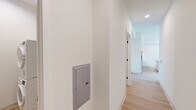 Located at 1529 N Fremont Street in Chicago's Lincoln Park neighborhood, this modern single-floor unit offers a thoughtfully designed open-concept layout. The combined kitchen and living area serves as the heart of the space, finished with light hardwood flooring throughout that creates a warm, cohesive feel. Large windows flood the interior with abundant natural light, enhancing the bright, airy ambiance created by the clean white walls and minimalist aesthetic.

The kitchen is well-appointed with flat-front cabinetry in a soft gray tone, stainless steel appliances including a gas range and refrigerator, a white quartz countertop, and a central island that provides additional prep space and storage. A wall-mounted mini-split HVAC unit ensures efficient climate control year-round.

The bathroom features a clean, contemporary design with wood-toned cabinetry, a white countertop vanity, black matte fixtures, and a glass shelf, maintaining the modern character found throughout the unit. A dedicated laundry area accommodates a stacked washer and dryer, adding everyday convenience. The overall design emphasizes functionality and clean lines, making this a practical and stylish urban residence.