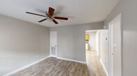 Located on Burgess Drive in Dalton, Georgia, this single-story, 2-bedroom, 1-bathroom home offers a straightforward and functional layout designed for comfortable everyday living. Wood-look luxury vinyl flooring runs consistently throughout the home, creating a cohesive and easy-to-maintain interior.

The living room serves as the central gathering space, featuring a ceiling fan with light fixture, neutral gray walls, and a front-facing window with blinds that allows natural light to fill the room. A paneled entry door provides direct access from outside.

The kitchen is well-appointed with warm honey-toned wood cabinetry, a mosaic tile backsplash, dark laminate countertops, and white appliances including an electric range, built-in microwave, and dishwasher. A window above the sink brings in additional natural light, and a flush-mount fluorescent light fixture illuminates the workspace. A large double-door closet adjacent to the kitchen offers generous storage.

Both bedrooms are comfortably proportioned, each equipped with a ceiling fan and windows with blinds. The primary bedroom offers a notably spacious feel with good natural light. The second bedroom is cozy and well-lit.

The bathroom features a clean, white tub and shower unit with chrome fixtures. Neutral tones and consistent finishes throughout give this home a tidy, move-in-ready appearance.