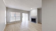This single-floor residence offers a cohesive and modern interior design throughout. The living area serves as the centerpiece of the home, featuring light wood-style flooring, a textured ceiling, and a tile-surround fireplace with a clean white mantel. Large windows with horizontal blinds and a sliding glass door with vertical blinds flood the space with natural light and provide access to the outdoors.

The galley-style kitchen is well-equipped with gray cabinetry, white quartz countertops, a subway tile backsplash, stainless steel appliances including a refrigerator, electric range, microwave, and dishwasher, as well as a stainless steel sink. The kitchen connects seamlessly to the rest of the living space.

The bedrooms are generously proportioned, each featuring light wood flooring, neutral gray walls, and wide windows that bring in ample natural light. Several bedrooms include mirrored sliding closet doors and ceiling fans, offering practical storage and comfort.

The bathrooms maintain the same refined aesthetic, with gray cabinetry, white countertops, and large-format gray tile surrounding the bathtub and shower areas. The primary bathroom features an expansive L-shaped vanity with a lighted mirror. Light wood flooring carries through the bathrooms, tying the design together cohesively throughout the home.