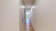 Located at 1501 S Acoma St in Denver, CO, this one-bedroom, one-bathroom unit offers a thoughtfully designed layout across a single floor. The open living and kitchen area features eye-catching herringbone-patterned hardwood flooring and recessed lighting that brightens the space throughout. The kitchen is outfitted with light wood cabinetry, stainless steel appliances including a refrigerator, range, microwave, and sink, providing a fully functional cooking space that flows seamlessly into the living area.

The bedroom is a generously sized room relative to the overall footprint, continuing the warm herringbone hardwood flooring. It features recessed lighting, a ceiling fan, and angled architectural ceiling details that add a distinctive character. A window allows for natural light and ventilation, complemented by a wall-mounted HVAC unit.

The bathroom maintains a clean, modern aesthetic with white tile surround enclosing a full bathtub and overhead shower. Brushed nickel fixtures, including towel rings and grab bars, accent the space, while light wood cabinetry beneath the vanity mirrors the design language found throughout the unit. The light hardwood flooring ties the bathroom into the cohesive style of the home, creating a uniform and polished overall ambiance.