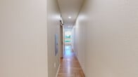 Located at 1501 S Acoma St in Denver, CO, this one-bedroom, one-bathroom unit offers a thoughtfully designed layout across a single floor. The open living and kitchen area features eye-catching herringbone-patterned hardwood flooring and recessed lighting that brightens the space throughout. The kitchen is outfitted with light wood cabinetry, stainless steel appliances including a refrigerator, range, microwave, and sink, providing a fully functional cooking space that flows seamlessly into the living area.

The bedroom is a generously sized room relative to the overall footprint, continuing the warm herringbone hardwood flooring. It features recessed lighting, a ceiling fan, and angled architectural ceiling details that add a distinctive character. A window allows for natural light and ventilation, complemented by a wall-mounted HVAC unit.

The bathroom maintains a clean, modern aesthetic with white tile surround enclosing a full bathtub and overhead shower. Brushed nickel fixtures, including towel rings and grab bars, accent the space, while light wood cabinetry beneath the vanity mirrors the design language found throughout the unit. The light hardwood flooring ties the bathroom into the cohesive style of the home, creating a uniform and polished overall ambiance.