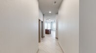 Located at 3000 Seventh Ave S in Birmingham, Alabama, this single-floor unit showcases a clean, contemporary design with a thoughtfully planned open layout. Light-toned luxury vinyl plank flooring runs throughout the main living areas, complementing the neutral color palette and creating a cohesive, modern aesthetic.

The kitchen serves as a focal point of the space, featuring flat-front wood-grain cabinetry extending to the ceiling, stainless steel appliances, a mosaic tile backsplash, and a large center island with a quartz countertop and undermount sink. Track lighting overhead highlights the workspace, while the open configuration allows seamless flow into the living area, which benefits from multiple windows that invite generous natural light.

A hallway connects the main living zone to the private quarters. The bedroom features soft carpeting, a ceiling fan, and a sliding barn door that opens to a bathroom with a tub/shower combination clad in large-format tile, built-in shelving, a wood-tone vanity, and recessed lighting. A second bathroom offers a glass-enclosed shower, dual-sink vanity with a wood-framed mirror, and tile flooring. Additional conveniences include an in-unit stacked washer and dryer tucked behind a sliding barn door.