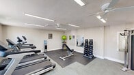 Located at 1515 S Yale St in Flagstaff, Arizona, this fitness center offers a well-equipped, single-room exercise space designed to accommodate a full range of workout routines. The room features light-toned luxury vinyl plank flooring, neutral-colored walls, and a textured ceiling fitted with bright linear LED lighting panels and a ceiling fan to ensure a comfortable environment during workouts.

The cardio zone is equipped with multiple Spirit-brand treadmills, an elliptical machine, and a recumbent stationary bike, providing versatile options for aerobic exercise. A dedicated strength training area features a multi-function cable machine and a freestanding pull-up and dip station. A full dumbbell rack with a comprehensive range of weights, paired with floor mats, supports free weight and functional training. Large wall-mounted mirrors on one side of the room enhance the sense of space and allow users to monitor their form.

Natural light filters through several windows, offering views of the surrounding Flagstaff landscape. A water cooler station is conveniently positioned within the room for hydration. The space is accessed through a secure keypad-entry door. Informational and safety signage, including a posted workout rules board and fire safety equipment, are thoughtfully integrated throughout the room, ensuring a safe and informative fitness environment.