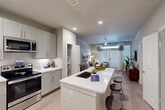 Located at 2926 Barker Cypress Rd in Houston, TX, this efficient one-bedroom, one-bathroom residence offers a thoughtfully designed open-concept floor plan that maximizes every square foot. The kitchen is a standout feature, boasting sleek gray shaker cabinetry, quartz countertops, a large center island with an undermount sink and bar seating, and a full suite of stainless steel appliances including a gas range, built-in microwave, and side-by-side refrigerator with ice maker. Light wood-style flooring flows throughout the main living areas, creating a cohesive and contemporary aesthetic. The living room is bright and welcoming, anchored by a ceiling fan and floor-to-ceiling windows with a glass door that invites natural light and provides direct outdoor access. The bedroom offers a comfortable retreat with plush carpeting, a ceiling fan, a large window with sheer drapery, and a dedicated closet. The bathroom is finished with tile flooring, a soaking tub and shower combo with decorative tile surround, and quartz vanity surfaces. A stacked in-unit washer and dryer adds everyday convenience. Recessed lighting and neutral tones throughout lend the space a clean, modern ambiance.