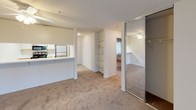 This 2-bedroom, 2-bathroom single-floor unit features a practical, efficient layout designed to maximize usable living space. The kitchen is equipped with stainless steel appliances, including a refrigerator and range, complemented by light-toned countertops and white cabinetry. A pass-through counter connects the kitchen to the main living area, creating an open, communicative flow between spaces. Adjacent to the kitchen, a dedicated laundry or utility alcove provides added convenience.

The living area is finished with wall-to-wall carpeting and neutral wall tones, contributing to a clean, understated ambiance. Built-in open shelving offers practical storage, while a mirrored sliding closet adds depth and functionality. A ceiling fan with integrated lighting serves the secondary bedroom, which also features baseboard heating and a window with leafy outdoor views. The primary bedroom similarly benefits from natural light and baseboard heating.

Both bathrooms are finished with tile flooring and feature tub-shower combinations enclosed by sliding glass doors. Each bathroom includes a window for natural ventilation. One bathroom features a speckled quartz-style countertop vanity, while both maintain a clean, bright aesthetic throughout.