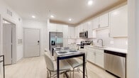 This well-appointed single-floor residence offers a thoughtfully designed layout that balances style and functionality. The kitchen serves as a centerpiece of the home, showcasing crisp white shaker cabinetry extending to the ceiling, a classic white subway tile backsplash, and a full suite of stainless steel appliances including a french door refrigerator, range, microwave, and dishwasher. Light wood-tone flooring flows throughout, lending a clean, contemporary aesthetic. The kitchen opens directly to a dedicated dining area, creating an effortless space for everyday meals or entertaining.

The living room is bright and welcoming, featuring a ceiling fan, light-toned walls, and a glass-paned door that leads to a private balcony overlooking greenery, allowing natural light to fill the space.

Two bedrooms offer comfortable retreats, with carpeted flooring and windows dressed with blinds and sheer curtains for adjustable light and privacy. The bathroom features a white vanity with ample counter space, a well-sized mirror, and clean, neutral finishes throughout.

A dedicated in-unit laundry room with a full-size washer and dryer adds a practical convenience. Overall, the unit presents a modern, cohesive design with a light and airy ambiance suitable for comfortable everyday living.