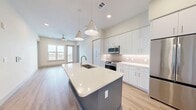 Located at 5440 W Tyson Ave in Tampa, FL, this well-appointed two-bedroom, two-bathroom residence offers a thoughtfully designed single-floor layout with modern finishes throughout. The open-concept kitchen serves as the heart of the home, showcasing a large quartz-topped island with an undermount sink and stylish pendant lighting, white shaker cabinetry, herringbone tile backsplash, and a full suite of stainless steel appliances including a French door refrigerator, range, and microwave. Light wood-look flooring flows seamlessly throughout the living areas, enhancing the bright, airy atmosphere. Both bedrooms are generously proportioned, benefiting from large windows that frame expansive outdoor views of the Tampa skyline and surrounding area. The primary bedroom includes a ceiling fan and access to a well-organized walk-in closet with built-in shelving and hanging systems. The primary bathroom features a double-sink vanity with quartz countertops, large-format tile flooring, and a soaking tub with classic subway tile surround. The second bathroom mirrors this clean aesthetic with a tub-shower combo and white vanity. A stacked in-unit washer and dryer adds everyday convenience, completing this refined and functional urban residence.