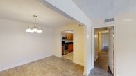 Located at 5600 Keele St in Jackson, Mississippi, this single-floor unit offers a practical and comfortable layout with consistent design elements throughout. The open dining area features wood-look laminate flooring and an elegant chandelier, flowing seamlessly into the kitchen through an arched passageway. The kitchen is well-appointed with warm honey-toned cabinetry, dark granite countertops, a double stainless steel sink, and stainless steel appliances including a range, microwave, and dishwasher. Tile flooring in the kitchen adds a clean contrast to the rest of the unit. The spacious living area continues the wood-look flooring theme and offers ample room for furniture arrangement. Bedrooms are bright and airy, each featuring neutral beige walls, wood-look floors, and windows with blinds that allow natural light to filter in. A dedicated hallway connects the private quarters to the main living spaces. The bathrooms are finished with tile flooring, white-tiled tub-shower combinations, and one includes a dark-stained vanity with an overhead light and mirror. Throughout the unit, clean white trim and soft warm-toned walls create a cohesive, welcoming ambiance.