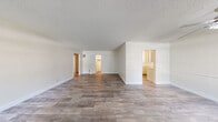 This single-floor residence offers a clean, functional layout with a consistent design language throughout. The expansive open living area serves as the heart of the home, finished with wood-look plank flooring and bright white walls that maximize the sense of space and light. A textured ceiling adds character, while multiple doorways connect seamlessly to the rest of the unit.

The kitchen is efficiently designed with white cabinetry, ample counter space, and a gas range, all illuminated by a window that brings in natural light. The layout makes practical use of every corner, providing solid storage and workspace.

The bedrooms are well-proportioned, each featuring wood-look flooring, ceiling fans, and mirrored sliding closet doors that reflect light and enhance the sense of openness. Windows dressed with vertical blinds allow for privacy while maintaining brightness.

Two bathrooms serve the home. The primary bathroom includes a wide vanity with white cabinetry, a large mirror, and a tiled walk-in shower with a glass door. The secondary bathroom features a combined tub and shower with tiled surround and a frosted window for natural light. Both bathrooms are finished with clean, neutral tones. Overall, the space presents a bright, move-in-ready environment with practical design throughout.