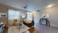 This two-story residence in Lexington, Kentucky offers a thoughtfully designed layout with modern finishes and a warm, cohesive aesthetic throughout. The main level centers around a bright, open living area finished with rich hardwood-style flooring, neutral warm-toned walls, and multiple windows that allow abundant natural light to fill the space. A ceiling fan overhead and a classic white staircase leading to the upper level add both function and character to the room. The kitchen is well-equipped, featuring dark espresso cabinetry, granite-style countertops, stainless steel appliances including a range, microwave, and dishwasher, along with a double sink — providing ample storage and prep space. A convenient full bathroom on the main level features a dark vanity with granite countertops, tile flooring, and a lighted mirror. Upstairs, the bedrooms are carpeted for comfort and each offer generous window coverage for natural light, making them well-suited for rest or use as a personal workspace. The upper-level bathrooms mirror the refined finishes seen throughout, with matching dark cabinetry and granite countertops. Overall, the space presents a consistent, contemporary design with practical features tailored for comfortable everyday living.