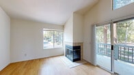 Located in Pleasant Hill, CA (94523), this single-floor residence combines clean, modern design with comfortable living across a well-organized layout. Warm hardwood flooring runs throughout the entire space, creating a cohesive and inviting atmosphere from room to room.

The living area is a standout feature, boasting soaring vaulted ceilings that lend an airy, open feel. A tile-surround fireplace with glass doors serves as a natural focal point, while a large window and sliding glass doors flood the room with natural light and frame views of surrounding mature trees. The sliding doors open to a private balcony, further enhancing the connection to the outdoors.

The kitchen is efficiently designed with white cabinetry, dark countertops, a full suite of white appliances including a refrigerator, electric range, microwave, and dishwasher, and a double sink. Overhead lighting keeps the space bright and functional.

The bedrooms are bright and simply finished with clean white walls, hardwood floors, and windows that bring in natural light and neighborhood views. The bathroom features a full tub-shower combination, a white vanity with dark countertop, and chrome fixtures, offering a clean and practical design. The overall ambiance of the space is light, neutral, and move-in ready.