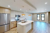Located at 625 Jackson Ave in New Orleans, LA, this thoughtfully designed one-bedroom, one-bathroom unit offers a modern open-concept layout with quality finishes throughout. Light-toned hardwood flooring flows seamlessly across the entire space, complementing the neutral warm-beige walls and crisp white trim.

The combined kitchen, dining, and living area forms the heart of the unit. The kitchen is equipped with stainless steel appliances — including a gas range, built-in microwave, and French door refrigerator — set against a mix of warm wood and matte cabinetry. A white quartz waterfall island with an integrated sink provides ample prep space and casual dining potential, while two striking orange pendant lights add a bold design accent overhead.

The spacious bedroom features three tall, black-framed windows that invite abundant natural light and offer elevated views of the surrounding New Orleans cityscape. A sleek black ceiling fan with integrated lighting adds both style and comfort. The bedroom includes access to a generously sized walk-in closet with built-in shelving.

The bathroom is finished with large-format white tile and a frameless glass walk-in shower with chrome fixtures. Additional conveniences include an in-unit laundry area and recessed lighting throughout.