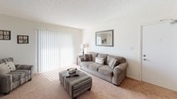 Located at 3044 Tobacco Rd in Augusta, Georgia, this single-floor residence offers a thoughtfully designed layout with comfortable, functional living spaces throughout. The living room is a welcoming retreat, featuring plush carpeting, large sliding glass doors fitted with vertical blinds that invite an abundance of natural light, and ample space for relaxed seating arrangements. Adjacent to the living area, a dedicated dining space provides a seamless connection to the kitchen through a convenient pass-through counter, making entertaining and everyday dining equally practical. The galley-style kitchen is well-equipped, showcasing warm wood cabinetry, granite countertops, a double-basin sink, and black appliances including a refrigerator and range. Tile flooring in the kitchen adds durability and ease of maintenance. The bedroom is a cozy and tranquil space, carpeted and lit by a natural-light window with curtains, accompanied by a closet with built-in shelving for organized storage. A dedicated in-unit laundry closet houses a full-sized washer and dryer, adding everyday convenience. The bathroom features tile flooring, a granite-topped vanity with warm wood cabinetry, and clean white walls that contribute to a bright, tidy atmosphere. Throughout, the home maintains a consistent, neutral palette that creates a cohesive and inviting ambiance.
