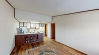 This one-bedroom, one-bathroom unit in Columbus, Ohio offers a functional and well-organized single-floor layout. The open-concept kitchen and living area forms the heart of the home, featuring warm wood-toned cabinetry with white upper cabinets, a built-in peninsula with open shelving, overhead fluorescent lighting, and white appliances including a refrigerator, electric range, and dishwasher. Hardwood-style flooring runs throughout the main living areas, complemented by rich wood trim and crown molding that add a classic, cohesive look. The living area receives natural light through a large window framed by matching wood trim, with a front entry door nearby. The bedroom is carpeted and includes a ceiling fan with light fixture, a window for natural light, and access to a closet. The bathroom is equipped with a tub-shower combination. A dedicated laundry room provides in-unit convenience with a full-size washer and dryer alongside a water heater. Two closets offer additional storage. Throughout the unit, textured ceilings and consistent wood trim detailing create a unified, practical living environment well-suited for everyday comfort.
