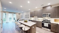 This thoughtfully designed one-bedroom, one-bathroom residence in Cherry Hill, New Jersey offers a modern open-concept layout with upscale finishes throughout. Light wood-tone flooring flows seamlessly across the main living areas, complemented by recessed lighting and a neutral color palette that creates a bright, airy ambiance. The combined kitchen and dining area is a standout feature, showcasing rich, dark wood cabinetry, crisp white quartz countertops, stainless steel appliances, and a generously sized island with bar seating — ideal for both cooking and entertaining. Decorative wall-mounted wine racks add a distinctive design touch to the dining area. The living room opens directly to a private balcony through full-height sliding glass doors, allowing abundant natural light and outdoor views. A versatile den provides additional flexible living space. The bedroom is a comfortable retreat with plush carpeting, a large window with outdoor views, and access to two closets. The bathroom features a wide double-sink vanity with dark wood cabinetry, a large framed mirror, and modern light fixtures. Additional highlights include a dedicated laundry room and a welcoming hallway that connects all areas of the home with ease.
