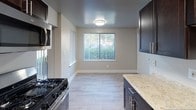 Located at 13913 Castle Blvd in Silver Spring, MD, this single-floor residence offers a well-organized layout with distinct living, sleeping, and kitchen areas. The galley-style kitchen is a notable highlight, featuring rich dark cabinetry, light stone countertops, a stainless steel sink, and a full suite of stainless steel appliances including a gas range, refrigerator, and microwave. Light wood-style flooring runs through the kitchen, which also benefits from a window overlooking the outdoors, bringing in natural light. An adjacent dining area provides additional flexibility.

The living area is generously proportioned, finished with neutral-toned carpet and large vertical-blind windows that allow ample natural light and outdoor views. A structural column adds architectural character to the open space, with easy-care hard-surface flooring near the entryway.

The bedroom is well-sized, offering carpeted floors, natural light through a large window, and access to a dedicated walk-in closet alongside additional storage. The bathroom features a full-size soaking tub with tiled surround, a curtain rod, grab bar, and a vanity with countertop space. Clean, neutral tones throughout the unit create a calm, functional ambiance.