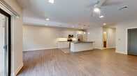 This contemporary 2-bedroom, 2-bathroom home at 5 Ledge Dr in Schenectady, NY offers a thoughtfully designed single-floor layout filled with modern finishes and functional living spaces. The open-concept kitchen and living area serves as the heart of the home, showcasing light wood-tone luxury vinyl plank flooring, recessed lighting, and a ceiling fan. The chef-inspired kitchen is equipped with stainless steel appliances, white shaker cabinetry, a subway tile backsplash, and a large center island with dark granite countertops and pendant lighting — ideal for both cooking and entertaining. The living room flows seamlessly toward sliding glass doors that open onto a private balcony with outdoor views. Both bedrooms feature plush carpeting, generous natural light, and modern dark-accented doors. The primary bedroom includes direct access to a sleek en-suite bathroom appointed with a glass-enclosed walk-in shower, a herringbone marble tile floor, a floating grey vanity, and stone tile accents. A dedicated laundry area houses a full-size front-loading washer and dryer beneath a dark countertop. The home also includes a closet and a second full bathroom, completing this well-appointed and move-in-ready residence.