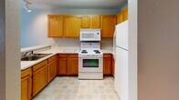 This single-floor unit offers a practical and well-organized layout designed for comfortable everyday living. The kitchen is equipped with warm oak cabinetry, ample counter space, a coil-burner electric range, an over-the-range microwave, a full-size refrigerator, and a sink — all finished with light tile flooring that is easy to maintain. A pass-through counter connects the kitchen to the adjacent living area, creating an open and sociable atmosphere. Track lighting overhead adds a functional brightness to the kitchen space.

The living area features soft wall-to-wall carpeting and flows naturally into a hallway that leads to the remaining rooms. A walk-in closet is conveniently located just off the main living space, providing generous storage. The bedroom is a comfortable, carpeted retreat highlighted by two arched windows that invite natural light and offer an airy feel. A ceiling fan, wall-mounted air conditioning unit, and baseboard heating ensure year-round climate control.

The full bathroom includes a soaking tub with a shower combination, a toilet, and a wood-toned vanity with a light countertop, complemented by tile flooring and textured walls. The overall design is clean, neutral, and move-in ready.