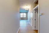 Located at 201–241 Spencer St in Syracuse, NY, this 2-bedroom, 2-bathroom residence offers a practical and well-organized single-floor layout. A welcoming hallway leads into the open living area, which is brightened by a window and finished with an elegant chandelier overhead. The neutral-toned walls and concrete-style flooring throughout lend the space a clean, modern aesthetic.

The kitchen is well-appointed with warm maple cabinetry, granite-look countertops, and a full suite of stainless steel appliances including a refrigerator, electric range, built-in microwave, and dishwasher. Track lighting above the kitchen adds functional illumination to the workspace.

The spacious primary bedroom offers generous proportions with neutral gray walls, carpeted flooring, and a wall-mounted heating unit. The second bedroom is similarly finished, providing a comfortable and versatile space. Both rooms benefit from convenient access to the four closets distributed throughout the unit, ensuring ample storage.

The two bathrooms are each equipped with a full tub-shower combination, vanity with stone-look countertops, and a clean, minimal design. The darker wall tones in the bathrooms contrast with the bright white fixtures to create a practical and well-defined space. Overall, the residence provides a functional and comfortable living environment in a straightforward, no-frills design.