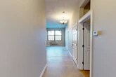 Located at 201–241 Spencer St in Syracuse, NY, this 2-bedroom, 2-bathroom residence offers a practical and well-organized single-floor layout. A welcoming hallway leads into the open living area, which is brightened by a window and finished with an elegant chandelier overhead. The neutral-toned walls and concrete-style flooring throughout lend the space a clean, modern aesthetic.

The kitchen is well-appointed with warm maple cabinetry, granite-look countertops, and a full suite of stainless steel appliances including a refrigerator, electric range, built-in microwave, and dishwasher. Track lighting above the kitchen adds functional illumination to the workspace.

The spacious primary bedroom offers generous proportions with neutral gray walls, carpeted flooring, and a wall-mounted heating unit. The second bedroom is similarly finished, providing a comfortable and versatile space. Both rooms benefit from convenient access to the four closets distributed throughout the unit, ensuring ample storage.

The two bathrooms are each equipped with a full tub-shower combination, vanity with stone-look countertops, and a clean, minimal design. The darker wall tones in the bathrooms contrast with the bright white fixtures to create a practical and well-defined space. Overall, the residence provides a functional and comfortable living environment in a straightforward, no-frills design.