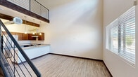 Located at 1571 North Pine Cliff Drive in Flagstaff, Arizona, this two-story, two-bedroom, two-bathroom home offers a thoughtfully designed layout spread across two well-proportioned floors. The main level opens to a bright, airy living area with soaring ceilings, light wood-look flooring, and abundant natural light from large windows. A distinctive exposed wood beam and industrial-style ductwork add architectural character to the open-concept kitchen, which features rich dark wood cabinetry, granite-style countertops, stainless steel appliances including a refrigerator and range, a peninsula with pendant lighting, and a built-in sink. A sleek black cable-rail staircase connects the two floors, adding a modern, open feel to the vertical space. Upstairs, the landing overlooks the main level and leads to two bedrooms, each with wood-look flooring, closets, and windows that bring in natural light. The two bathrooms are finished consistently with granite-style vanity tops and wood cabinetry. One bathroom features a tub-shower combination, while the second is equipped with an accessible roll-in shower and grab bars. Throughout, the home maintains a clean, modern aesthetic with neutral tones and quality finishes.