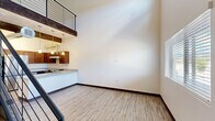 Located at 1571 North Pine Cliff Drive in Flagstaff, Arizona, this two-story, two-bedroom, two-bathroom home offers a thoughtfully designed layout spread across two well-proportioned floors. The main level opens to a bright, airy living area with soaring ceilings, light wood-look flooring, and abundant natural light from large windows. A distinctive exposed wood beam and industrial-style ductwork add architectural character to the open-concept kitchen, which features rich dark wood cabinetry, granite-style countertops, stainless steel appliances including a refrigerator and range, a peninsula with pendant lighting, and a built-in sink. A sleek black cable-rail staircase connects the two floors, adding a modern, open feel to the vertical space. Upstairs, the landing overlooks the main level and leads to two bedrooms, each with wood-look flooring, closets, and windows that bring in natural light. The two bathrooms are finished consistently with granite-style vanity tops and wood cabinetry. One bathroom features a tub-shower combination, while the second is equipped with an accessible roll-in shower and grab bars. Throughout, the home maintains a clean, modern aesthetic with neutral tones and quality finishes.