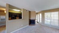 Located at 1109 Meadow Creek Dr in Irving, Texas, this single-story residence offers a well-organized layout with distinct living, kitchen, and bedroom areas. The entryway welcomes you with wood-look flooring that transitions into plush carpeting throughout the main living spaces, creating a warm and comfortable atmosphere.

The open living area is a central highlight, featuring a tile-surround fireplace with a raised hearth and a dedicated mantle shelf that serves as a natural focal point. Large windows with horizontal blinds line the far wall, allowing abundant natural light to brighten the space. The vaulted ceiling adds a sense of openness and volume to the room.

The kitchen is efficiently designed in a galley-style layout, showcasing dark espresso cabinetry, granite-style countertops, and black appliances including a refrigerator, electric range, microwave, and dishwasher. Wood-look flooring runs throughout the kitchen, complementing the rich cabinetry tones. A breakfast bar connects the kitchen to the living area, enhancing the open flow.

The bedrooms are carpeted and include ceiling fans and windows with outdoor views. The bathroom features a granite-style vanity with dark cabinetry, a large mirror, and a soaking tub enclosed by full-height earth-toned tile surround.