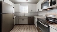 Located at 200 Knollridge Ct in Fairfield, Ohio, this single-floor home offers a thoughtfully updated interior with a cohesive, modern aesthetic throughout. The kitchen is a standout feature, showcasing two-tone cabinetry with crisp white upper cabinets and sage-gray lower cabinets, granite countertops, a classic white subway tile backsplash, and a full suite of stainless steel appliances including a refrigerator, range, microwave, and dishwasher. Wood-look plank flooring runs throughout the main living areas, providing both durability and visual warmth. The living area is open and inviting, with soft gray walls and direct sightlines into the kitchen. The bedrooms are generously sized, each featuring the same wood-look flooring, neutral gray walls, textured ceilings, and windows that bring in natural light. One bedroom includes a walk-in closet with built-in shelving and an attached bathroom. Both bathrooms are outfitted with tiled tub-shower combinations and chrome fixtures. The floor plan offers a well-connected layout that balances open communal spaces with private retreats, making this a functional and move-in ready home.