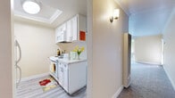 Located in Fremont, CA, this single-floor residence offers a clean, functional layout designed for comfortable everyday living. The interior is finished with warm beige walls, crown molding throughout, and plush grey carpeting that extends across the living and bedroom areas, lending a cohesive and cozy feel to the space.

The kitchen is compact yet efficiently designed, featuring white cabinetry, light stone-look countertops, a stainless steel sink, and white appliances including a range and refrigerator. A skylight above adds a welcome touch of natural light. The kitchen opens toward the living area, which is anchored by a ceiling fan and a pass-through counter, creating an open, connected atmosphere.

The living area is generously proportioned, with large windows and sliding glass doors fitted with vertical blinds that invite abundant natural light and offer views of the surrounding greenery and mature trees outside.

The bedroom is a well-sized retreat featuring a double sliding-door closet with built-in shelving, crown molding, and access to natural light through a windowed door. The full bathroom is neatly appointed with a white vanity, stone-look countertop, mirrored medicine cabinet, and a tub-shower combination with tiled surround. Wood-look flooring in the bathroom complements the home's overall clean aesthetic.