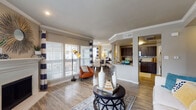 This two-story residence in Irving, Texas offers a thoughtfully designed layout spread across two levels. The main living area on the ground floor features an open-concept design where the living room, dining area, and kitchen flow seamlessly together. Wood-style flooring runs throughout the lower level, complementing the neutral color palette. Large windows allow generous natural light to fill the space, while bold navy and white striped curtains add a distinctive design element. A white-mantled fireplace serves as a focal point in the living area, adding both character and warmth.

The kitchen is equipped with dark espresso cabinetry, granite countertops, a tile backsplash, and stainless steel appliances, including a full-size refrigerator. A breakfast bar provides additional seating and further connects the kitchen to the living and dining spaces.

A carpeted staircase with a white balustrade leads to the upper level, where the bedrooms are located. The bedrooms feature plush carpet flooring, ceiling fans, and windows that bring in natural light. Bathrooms on both levels showcase granite countertops, dark cabinetry, and wood-style flooring, maintaining a consistent, cohesive aesthetic throughout the home.