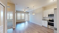 This single-floor unit offers three bedrooms and two bathrooms within a efficiently arranged floor plan. The open-concept kitchen and living area serves as the heart of the unit, where wood-style plank flooring flows seamlessly throughout the common spaces. The kitchen is equipped with stainless steel appliances—including a refrigerator, range, microwave, and dishwasher—complemented by white shaker-style cabinetry, granite-look countertops, a stainless steel sink, and recessed and track lighting overhead. A pendant light fixture marks the transition into the living area, which benefits from large windows and a glass door that invite generous natural light and outdoor views.

The bedrooms feature plush carpeting and ceiling fans, with the primary bedroom offering a notably spacious layout and access to a well-sized closet. The primary bathroom includes a double-sink vanity with granite-look countertops and wood-style flooring. The second bathroom features a single vanity and a walk-in shower. Neutral beige and white tones throughout lend the unit a clean, cohesive aesthetic, while six-panel interior doors add a classic architectural detail across all rooms.