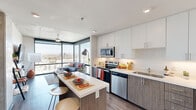 Located at 1000 East Apache Boulevard in Tempe, Arizona, this contemporary 2-bedroom, 2-bathroom residence offers a thoughtfully designed open-concept layout. The kitchen serves as the heart of the home, featuring sleek white upper cabinetry, wood-toned lower cabinets, quartz countertops, a full suite of stainless steel appliances, and a central island with bar seating — ideal for casual dining or entertaining. Floor-to-ceiling windows in the living area flood the space with natural light and frame sweeping views of the Tempe cityscape. Wood-style flooring runs throughout the main living areas, adding warmth and continuity. Each bedroom is well-proportioned, with large windows that bring in abundant natural light and elevated city views; one bedroom includes a walk-in closet with built-in shelving. Both bathrooms are finished with modern floating vanities, white quartz countertops, glass-enclosed walk-in showers, and tile flooring. A dedicated closet and hallway provide additional storage and connectivity throughout the unit. The overall aesthetic is clean, modern, and cohesive, making this a refined and functional urban residence in the heart of Tempe.