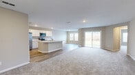 Located at 4903 Boundary Way in Jacksonville, FL, this single-story home offers a thoughtfully designed open-concept floor plan across three bedrooms, three bathrooms, and a generous living area. The combined kitchen and living room serves as the heart of the home, featuring wood-look hard flooring, recessed lighting, and large sliding glass doors that flood the space with natural light and provide views of the outdoors. The kitchen is equipped with stainless steel appliances — including a side-by-side refrigerator, range, and over-the-range microwave — white cabinetry, light countertops, and a central island ideal for meal prep or casual dining. The bedrooms offer comfortable carpeted flooring, neutral-toned walls, and ample natural light from well-placed windows. The spacious primary bedroom includes its own closet. Five closets throughout the home provide abundant storage. The three bathrooms are clean and functional, featuring tub-shower combinations and wood-look flooring. A dedicated laundry room houses a full-size washer and dryer with overhead wire shelving. The attached garage offers substantial space with a standard overhead door. The layout flows efficiently through two hallways, making this home both practical and comfortable for everyday living.