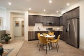This thoughtfully designed single-floor residence in Westminster, California, offers a cohesive blend of modern finishes and vibrant interior styling throughout. The kitchen is a standout feature, showcasing rich dark-toned cabinetry with gold hardware, sleek white quartz countertops, a subway tile backsplash, and a full suite of stainless steel appliances including a French door refrigerator, range, built-in microwave, and dishwasher. Light wood-style flooring and recessed lighting complete this functional yet attractive space, which flows seamlessly into a dedicated dining area. The living room exudes warmth with a distinctive textured wood-paneled accent wall, recessed lighting, and a large window that invites natural light. The bedrooms are generously sized, each with large windows offering outdoor views, plush carpeting, and ample closet space — including a spacious walk-in closet with built-in shelving and hanging rods. Two well-appointed bathrooms feature dark wood vanities with white quartz countertops, gold-accented mirrors and fixtures, and wood-style tile flooring. One bathroom includes a glass-enclosed shower. The unit also includes a convenient in-unit stacked Whirlpool washer and dryer, adding everyday practicality to this stylish Westminster residence.