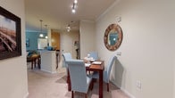 Located at 1475 Benton Blvd in Pooler, Georgia, this single-floor residence offers a thoughtfully designed open-concept layout with a warm, coastal-inspired aesthetic throughout. The living room serves as the heart of the home, featuring crown molding, soft carpet flooring, a ceiling fan, and calming blue-gray accent walls. Large windows and a glass exterior door flood the space with natural light, while an open passage connects seamlessly to additional rooms. The adjacent dining area provides an intimate setting with direct sightlines into the kitchen, anchored by a decorative round mirror on the wall. The galley-style kitchen is well-equipped, showcasing warm wood cabinetry, dark granite countertops, tile flooring, and black appliances including a refrigerator, range, microwave, and dishwasher. Track lighting illuminates the workspace, and a raised breakfast bar adds casual dining functionality. The bedrooms are carpeted and tranquil, each featuring ceiling fans, soft accent walls, and natural light from windows. The primary bedroom includes a walk-in closet. The bathroom features a double-sink vanity with granite countertops, matching wood cabinetry, tile flooring, and a tub-shower combination. Throughout the home, consistent finishes and a cohesive coastal color palette create a comfortable and polished living environment.