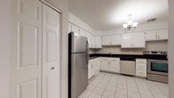 This two-floor residence in West Hartford, CT offers a practical and well-appointed layout throughout its two levels. The kitchen is a standout space, featuring white cabinetry, dark granite-style countertops, light tile flooring, and stainless steel appliances including a refrigerator, stove, and dishwasher. A chandelier adds a touch of elegance overhead. The living area is generously sized, with plush carpeting, a brick fireplace with built-in shelving, and a sliding glass door fitted with vertical blinds that opens to bring in natural light. A chandelier accentuates the room's welcoming ambiance. The bedrooms are carpeted and neutrally toned, with large windows that allow ample natural light to filter through. One room features an angled ceiling detail and a wide horizontal window, adding architectural character. The bathrooms are finished with white tile flooring and dark countertops, offering a clean, functional aesthetic, with one featuring a glass-door shower enclosure and accessibility grab bars. Throughout the space, neutral wall tones and consistent finishes create a cohesive feel. The two-floor configuration provides a clear separation of living areas, making this West Hartford residence both functional and comfortable.