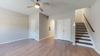 This two-story residence offers a thoughtfully laid-out floor plan with consistent, modern finishes throughout. Wood-look laminate flooring flows seamlessly across both levels, contributing to a clean and cohesive aesthetic. Neutral gray walls provide a versatile backdrop that complements the space's contemporary design.

The main level features a spacious living area illuminated by a ceiling fan with integrated lighting, along with access to a double-door closet and additional storage. The kitchen is a standout feature, showcasing rich dark espresso cabinetry, granite countertops, and a full suite of black appliances, including a refrigerator, gas range, dishwasher, and built-in microwave. The contrasting light flooring and sleek backsplash add visual depth to the kitchen's bold palette.

A full bathroom on this level includes a tub-shower combination, a dark-vanity with granite countertop, a large mirror, and tile flooring, maintaining the design consistency found throughout the home.

The upper level houses additional bedrooms, each finished with the same wood-look flooring and neutral tones. One bedroom features a window with natural light and views of the surrounding neighborhood, while another includes a ceiling fan. A separate walk-in shower bathroom serves the upper level. A staircase with wood treads and a railing connects both floors, adding a refined structural detail to the interior.